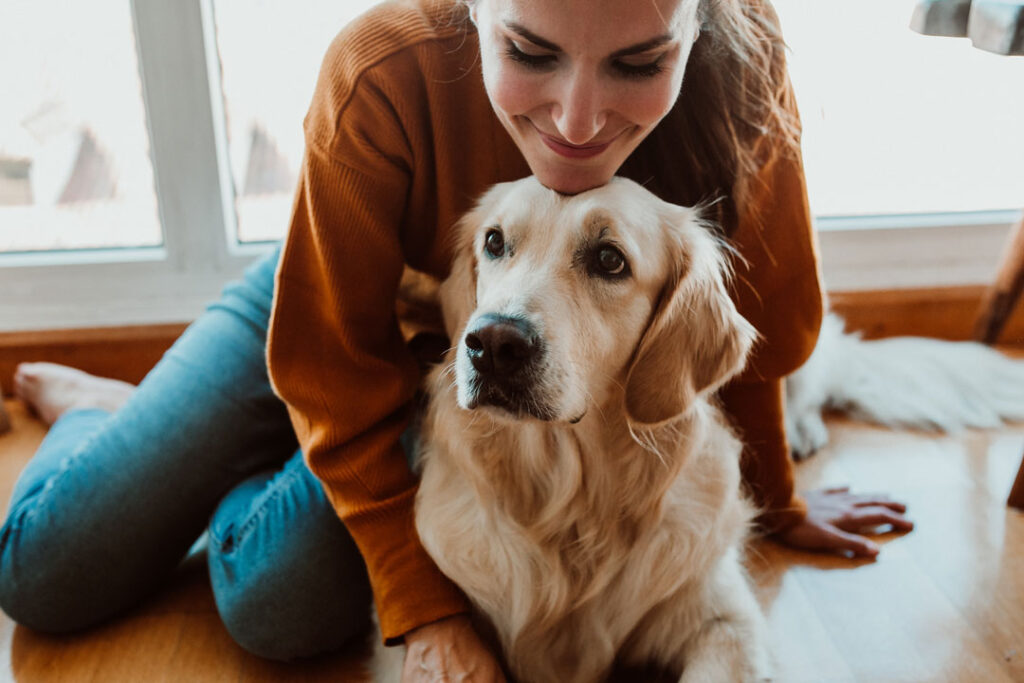 woman sitting on the floor petting her golden retriever